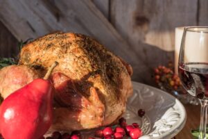 Close up of roasted turkey and wine pairing against rustic barn wood background,