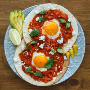 Mexican breakfast huevos rancheros: fried egg with salsa closeup in the pan